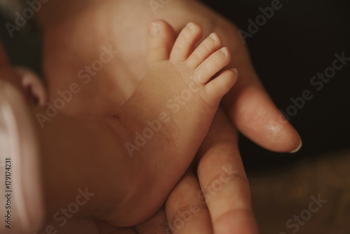 mother holds little foot of newborn baby