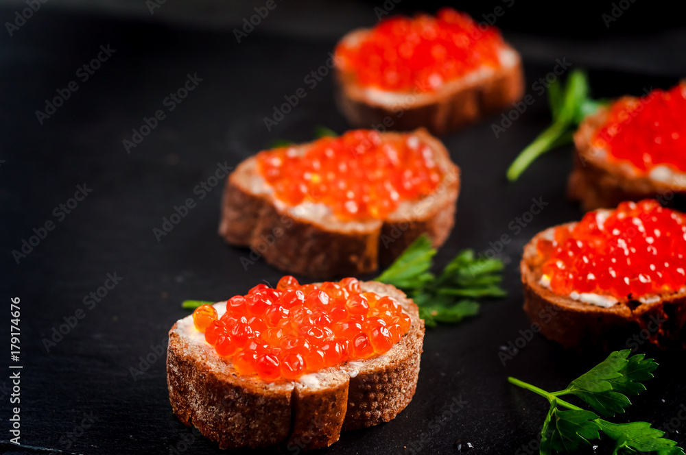 red caviar on black bread with butter. Healthy food. Fish appetizer. dark background red caviar on black bread with butter. Healthy food. Fish appetizer. dark background