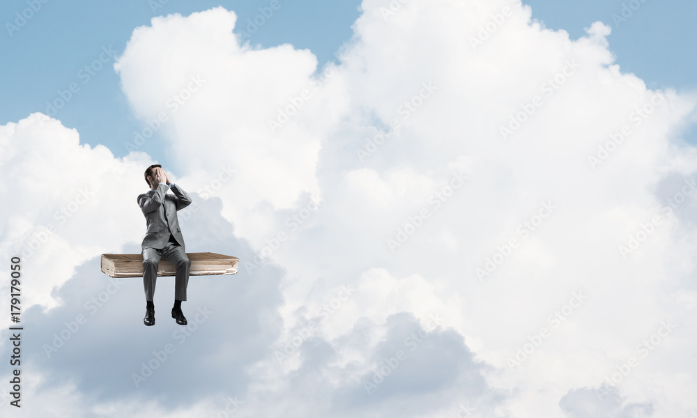 Young man on book in blue sky do not want to see anything Young man on book in blue sky do not want to see anything
