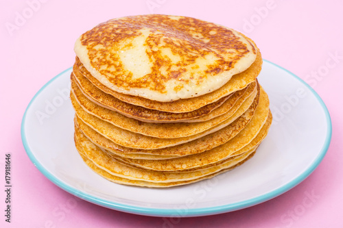High stack of fried pancakes on pink background