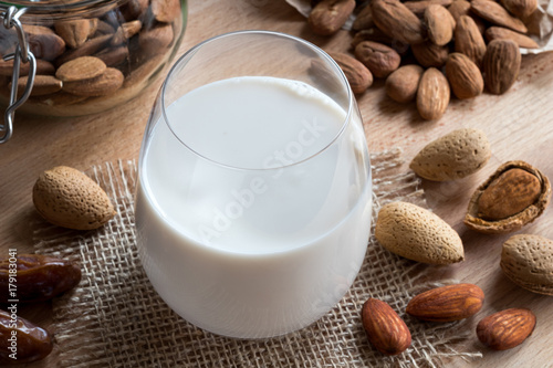 A glass of almond milk with whole and shelled almonds