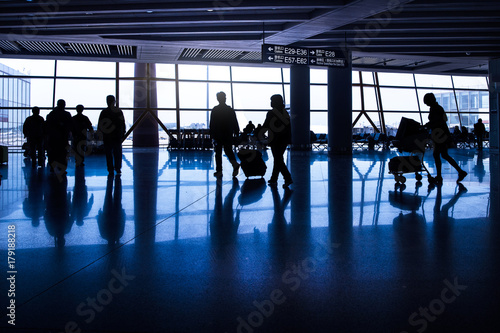 Silhouttes of passengers waiting in an asian airport and carrying their luggage