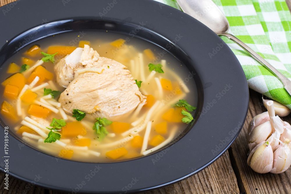 Soup with chicken, pumpkin and noodles on wooden table