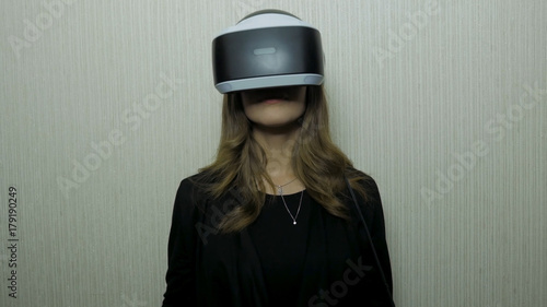 Woman using finger to touch on imaginary panel viewing on VR device against white wall. Girl use of vr device