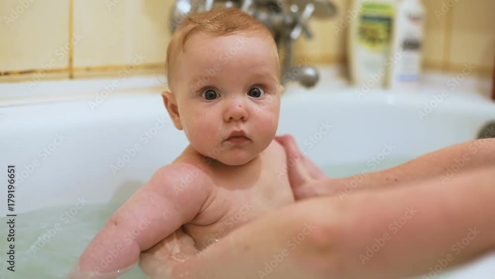 cute gentle toddler baby boy bathing white tub bathroom mother hands helping water surprised eyes nice face close up portrait looking camera calm child sweet chubby cheeks mom motherhood health caring cute gentle toddler baby boy bathing white tub bathroom mother hands helping water surprised eyes nice face close up portrait looking camera calm child sweet chubby cheeks mom motherhood health caring