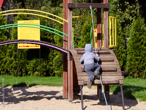 Mały chłopiec bawi się na placu zabaw w jesienny słoneczny dzień.