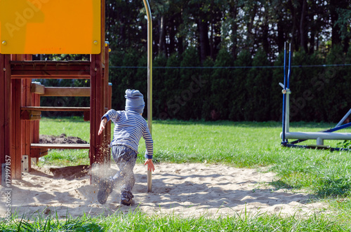 Mały chłopiec bawi się na placu zabaw w jesienny słoneczny dzień.