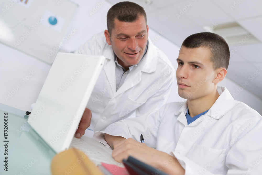male computer science student with teacher working on a laptop male computer science student with teacher working on a laptop