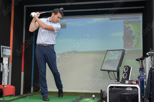Man practicing golf swing using simulator photo