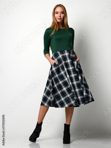 Young beautiful woman posing in new fashion plaid skirt and green blouse full body 
