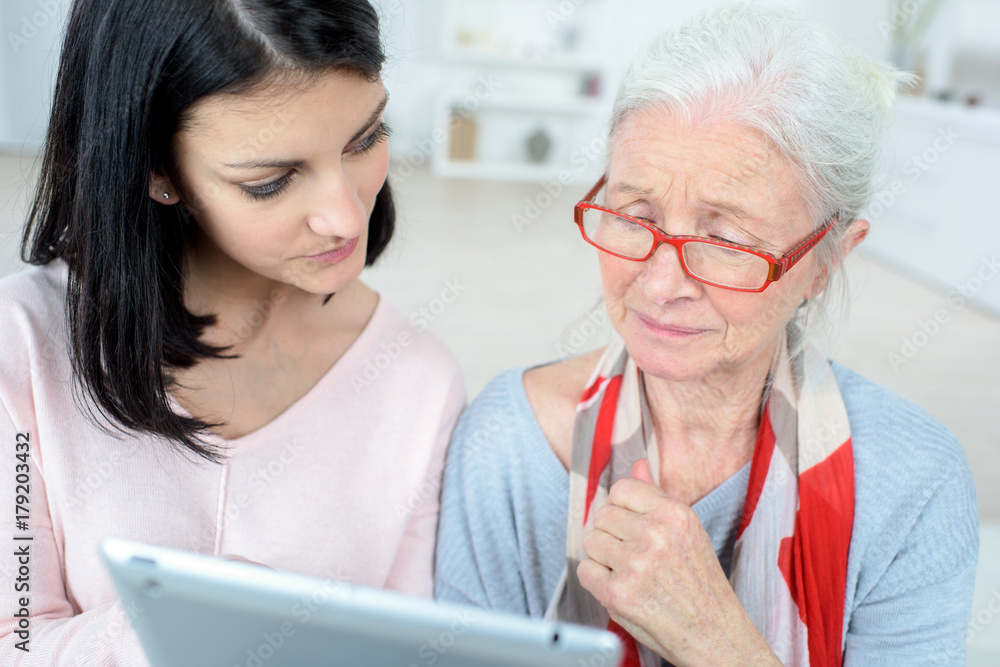 elderly woman and daughter reading their tablet elderly woman and daughter reading their tablet