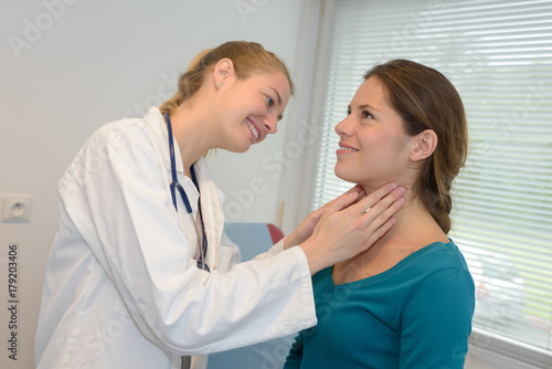 female doctor checking the throat of a young patient photo