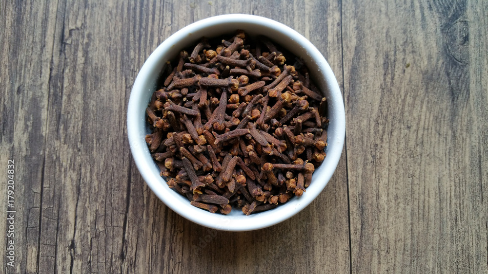 Cloves in white glass bowl on wooden background Cloves in white glass bowl on wooden background
