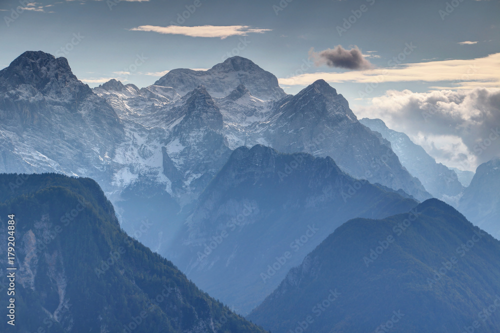 Highest peak of Slovenia the mighty snow covered Triglav towering over Rjavina, Begunjski vrh and Cmir north faces and steep glacial Kot Valley in blue mist, Triglav National Park, Julian Alps, Europe
