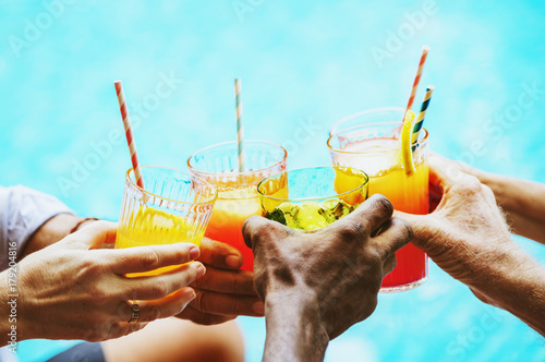 Closeup of diverse hands clinking drinks together