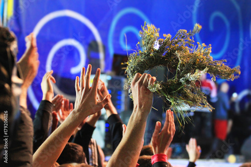 People waving hands and wreaths at a concert
