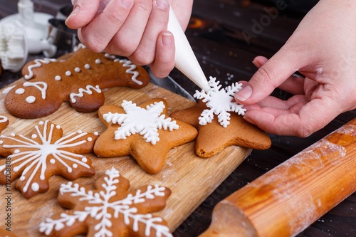 Christmas bakery. Process of decorating homemade gingerbread snowflakes with icing and confectionery mastic, close up. Festive culinary and New Year traditions concept