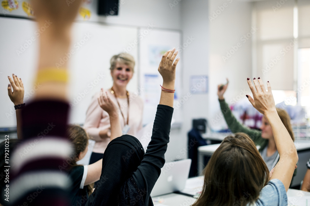 Students with their hands up responding to their teacher Students with their hands up responding to their teacher