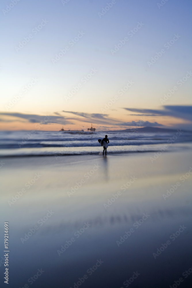 Silhouette of surfer holding surfboard during sunset Silhouette of surfer holding surfboard during sunset