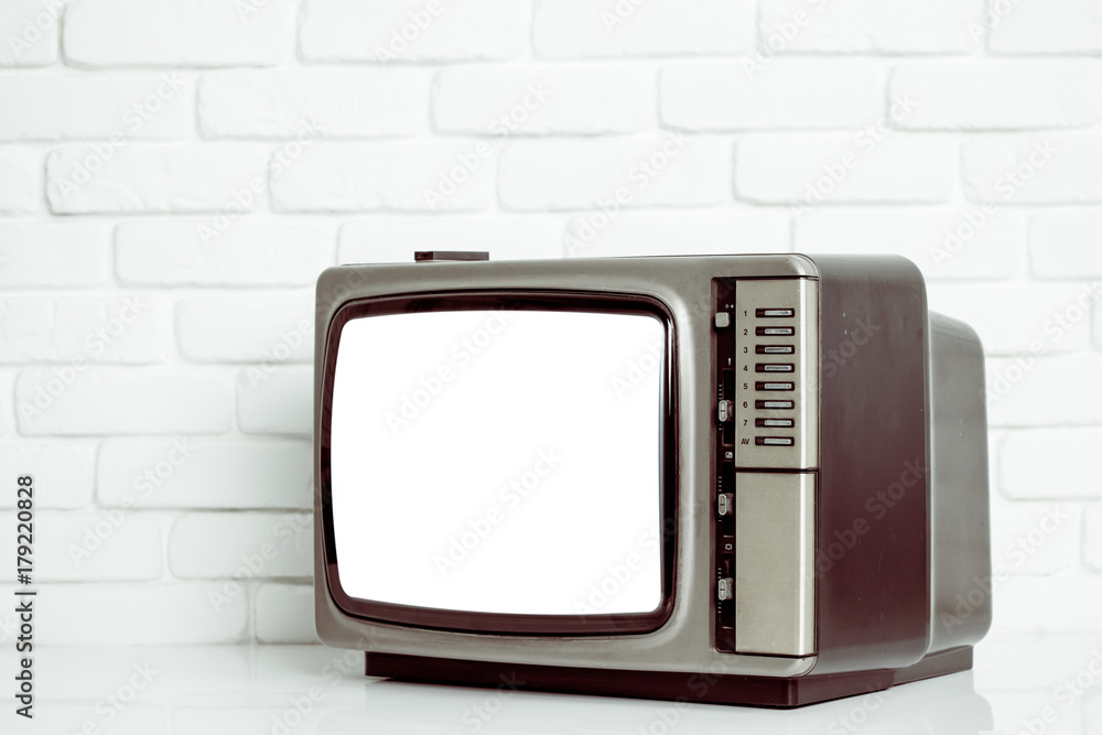 Old television with cut out screen on a white brick wall