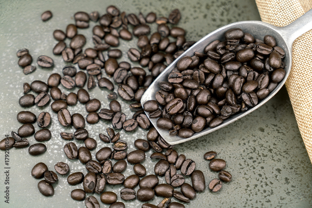 Fototapeta premium Close up of roast coffee beans in the scoop on the stone table background