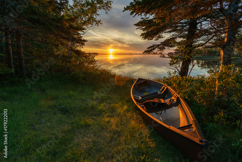 Fototapete Empty canoe at sunset