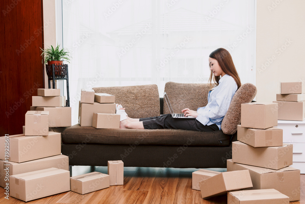Young woman holding laptop with cardboard box at home - Business online and delivery concept Young woman holding laptop with cardboard box at home - Business online and delivery concept