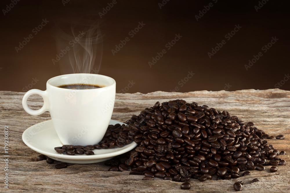 A cup of hot coffee on a wooden table with roasted coffee bean A cup of hot coffee on a wooden table with roasted coffee bean