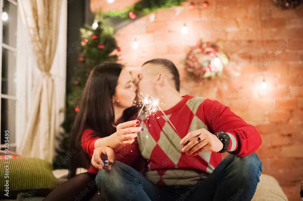 Male and female hands hold Bengal lights lit. Beautiful happy young family celebrating Christmas together. Lovers on the New Year together in an apartment in the Loft. Bedroom decorated in New Year's Male and female hands hold Bengal lights lit. Beautiful happy young family celebrating Christmas together. Lovers on the New Year together in an apartment in the Loft. Bedroom decorated in New Year's