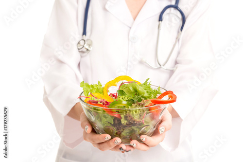 Woman doctor holding a plate with fresh vegetables salad for you isolated on white background