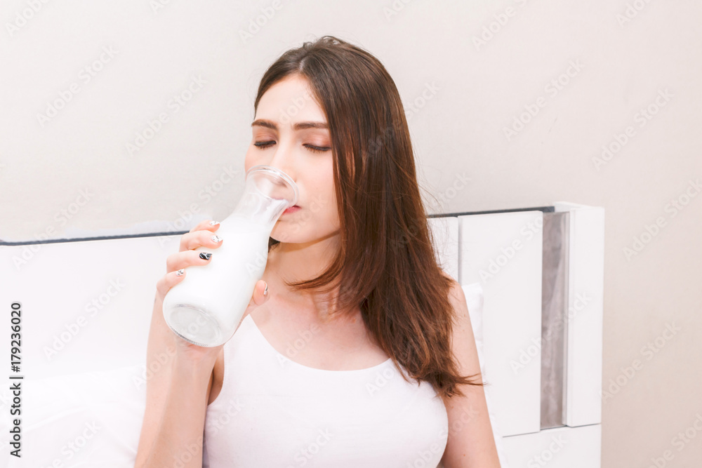 Young woman drinking milk on her bed.healthy lifestyle concept Young woman drinking milk on her bed.healthy lifestyle concept