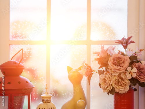Fototapeta Naklejka Na Ścianę i Meble -  Flowers in vase with  ceramic cat on window in the evening light