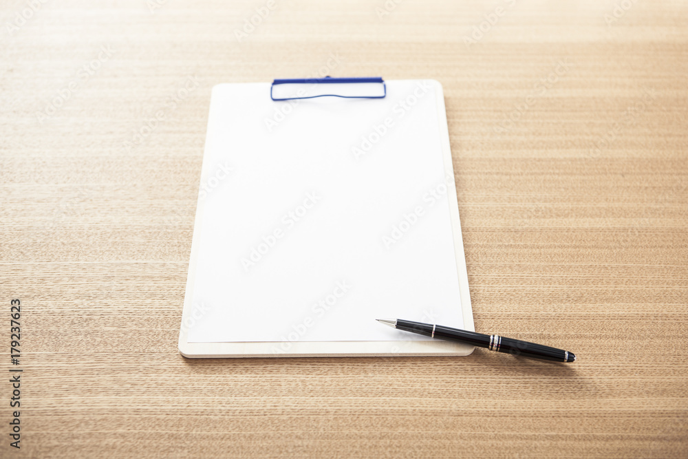 clipboard with stationarys on the wood desk(table) at the day light. clipboard with stationarys on the wood desk(table) at the day light.