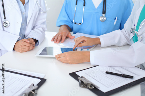 Group of doctors at medical meeting. Close up of physician using touch pad or tablet computer photo