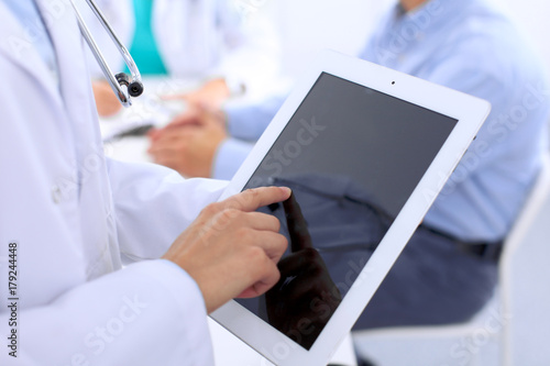 Doctor using tablet computer, close-up of hands at touch pad screen