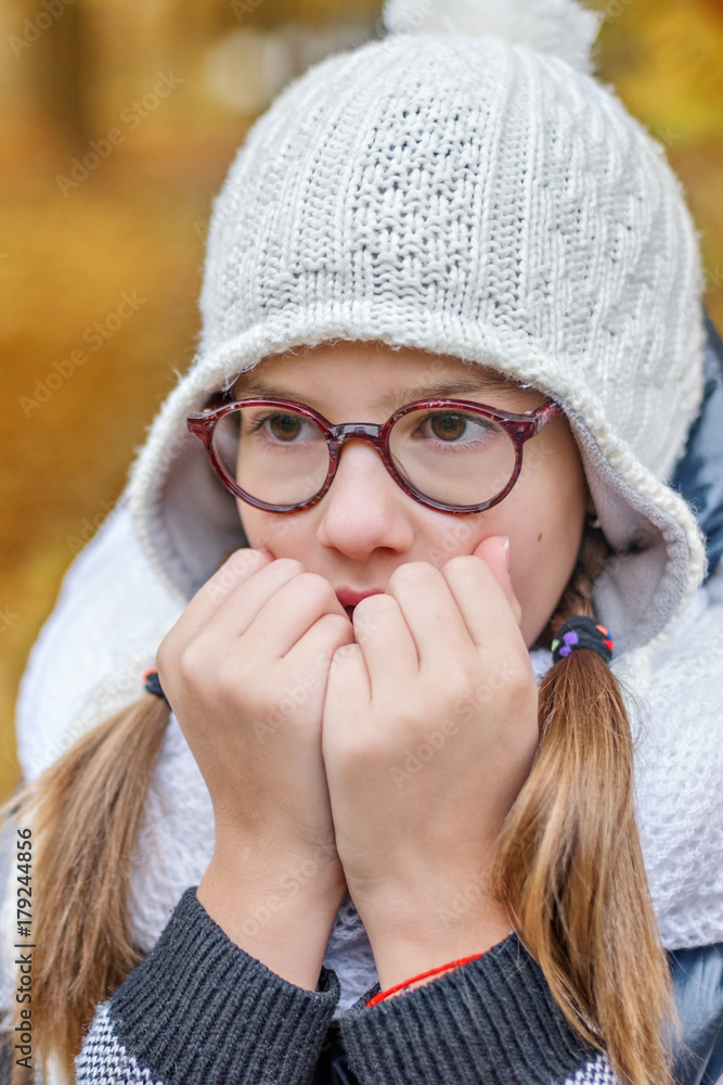 portrait of teenage girl in glasses, blowing on her hands to keep warm in the cold portrait of teenage girl in glasses, blowing on her hands to keep warm in the cold