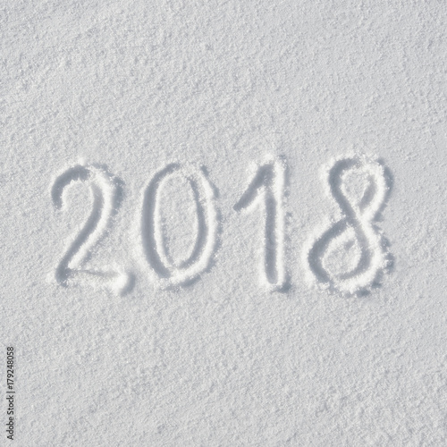 2018 text letters handwritten on flat snow surface. New year holiday seasonal postcard, greeting card.