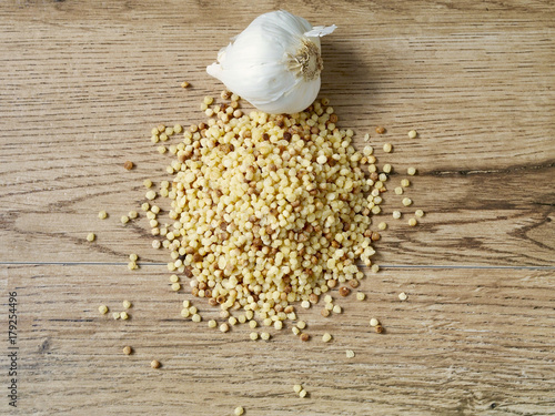 Raw fregola with garlic on wood background photo