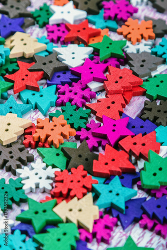 different color buttons in the shape of Christmas trees and snowflakes on the table. the scenery for the Christmas holiday