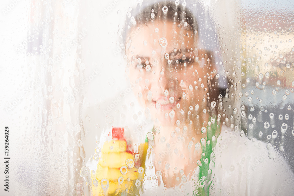 Female cleaner or housewife washing window with spray