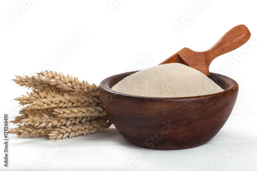 wheat semolina in a wooden bowl on a white table