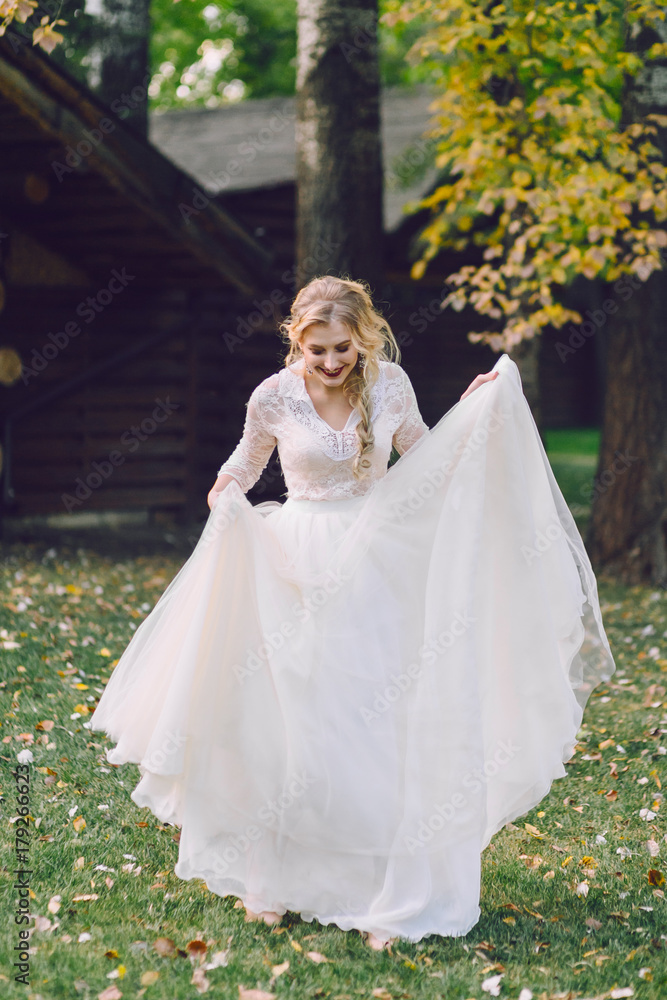 Fototapeta premium Happy bride is posing in fluttering dress on nature. Artwork
