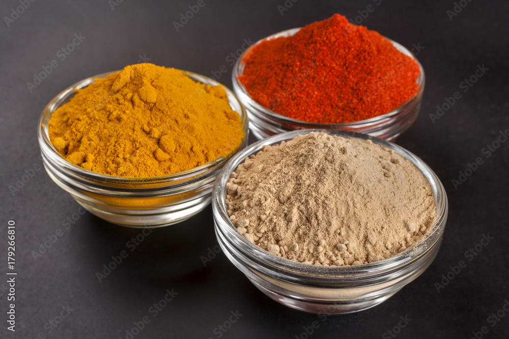 spices from ginger, turmeric and red peppers on a black background spices from ginger, turmeric and red peppers on a black background