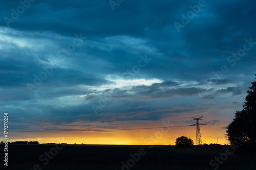High voltage power lines and transmission towers at sunset. Poles and overhead power lines silhouettes in the dusk. Electricity generation and distribution. Electric power industry and nature concept © sergiymolchenko