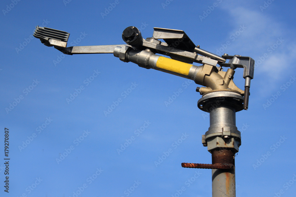 Rotating water spraying cannon against blue sky background Rotating water spraying cannon against blue sky background