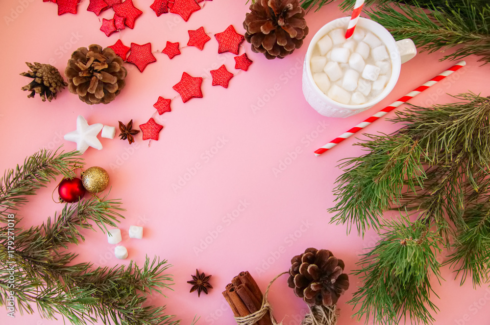Obraz premium Christmas background with copy space, fir tree branches, hot chocolate with marshmallows, anise, cinnamon, pine cones, red star garland. Pink backdrop.