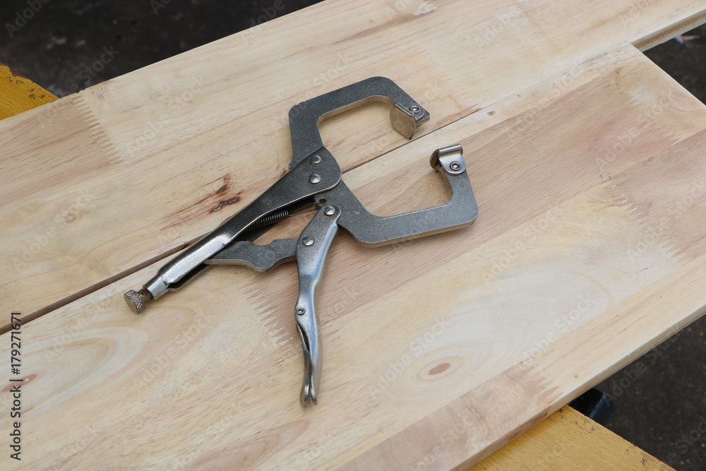 Metal vise grip locking clamp on wooden background Metal vise grip locking clamp on wooden background