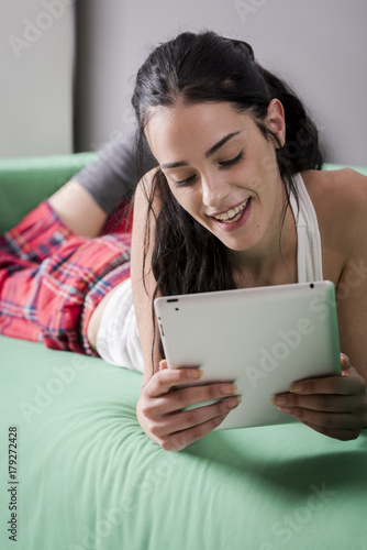 Smiling pretty woman lying with tablet