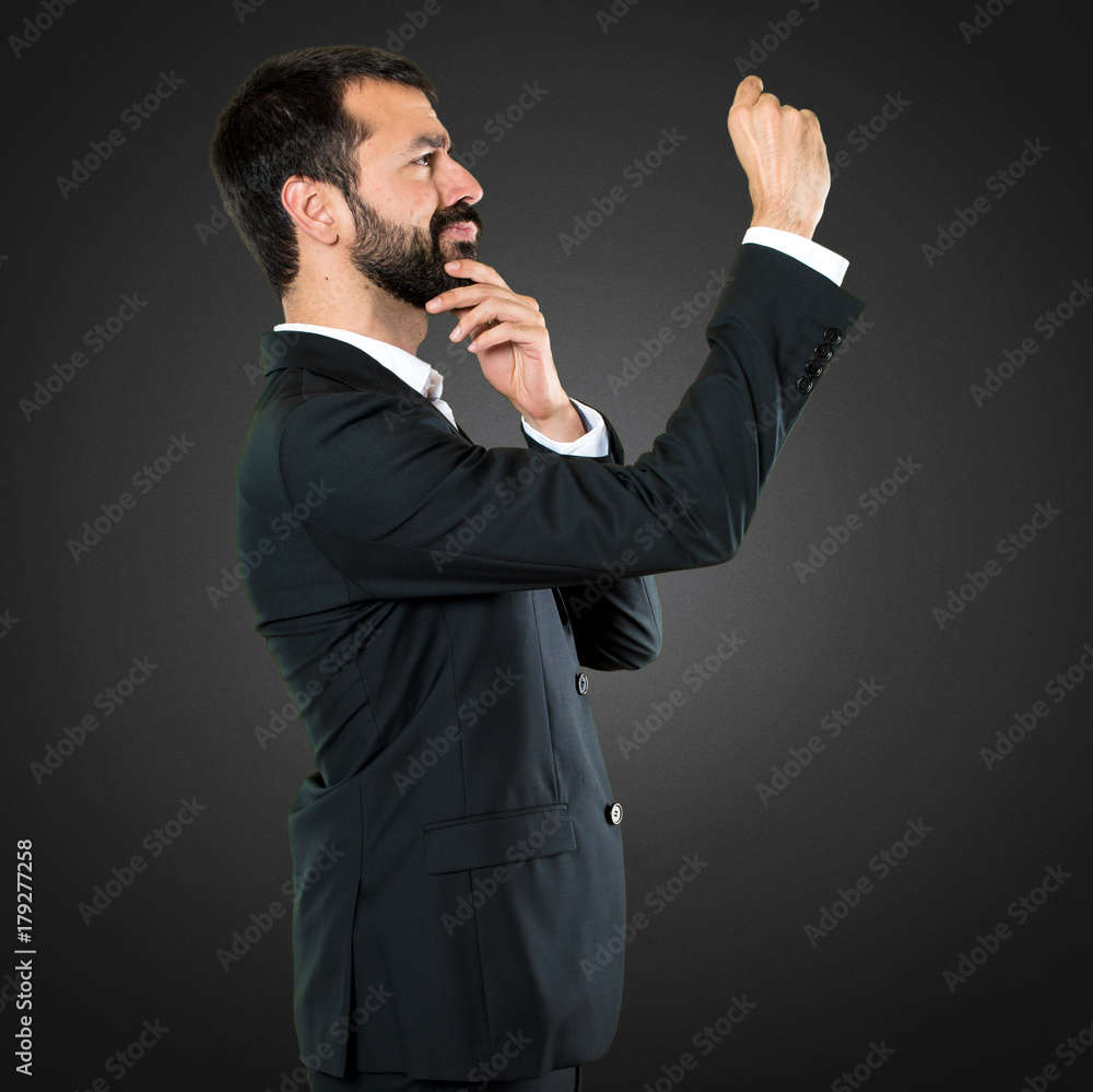 Handsome businessman making tiny sign on black background Handsome businessman making tiny sign on black background