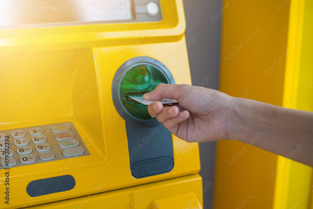 Hand inserting ATM card into bank machine to withdraw money.